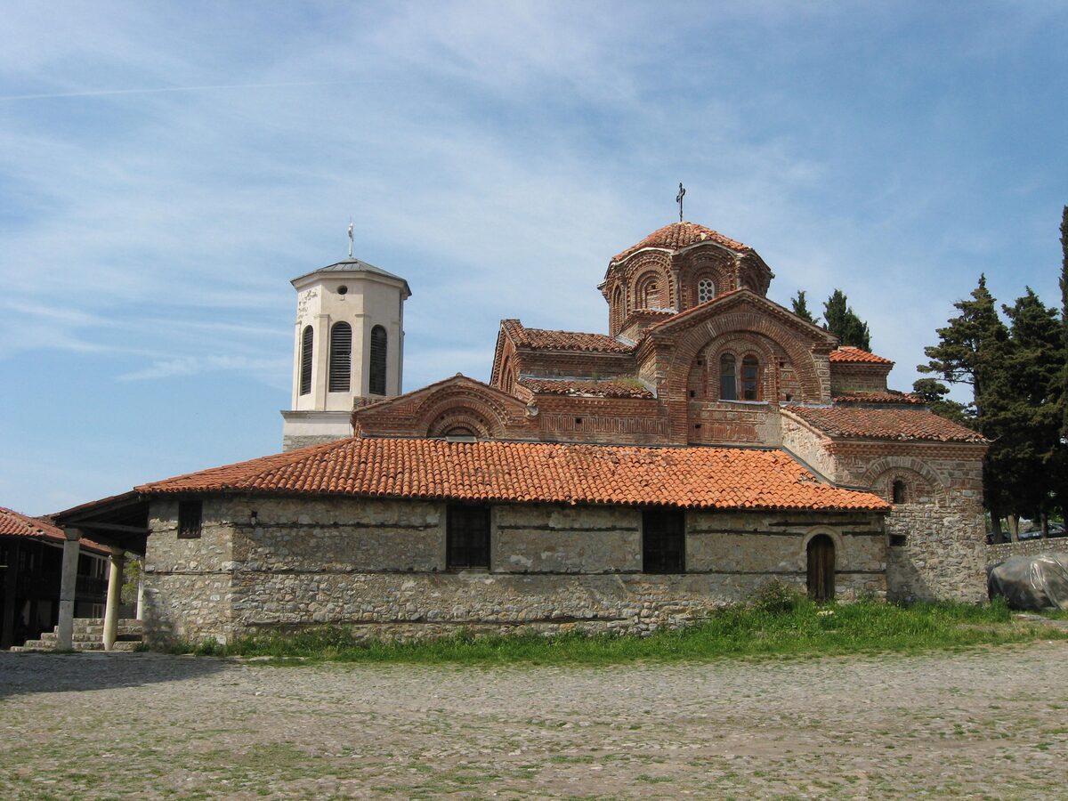 The stone church of Perivleptos with its terracotta roof and white bell tower, seen from the courtyard