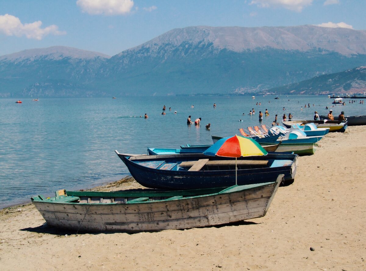 Fishing boats pulled up on the sand of the Pogradec beach with the lake behind