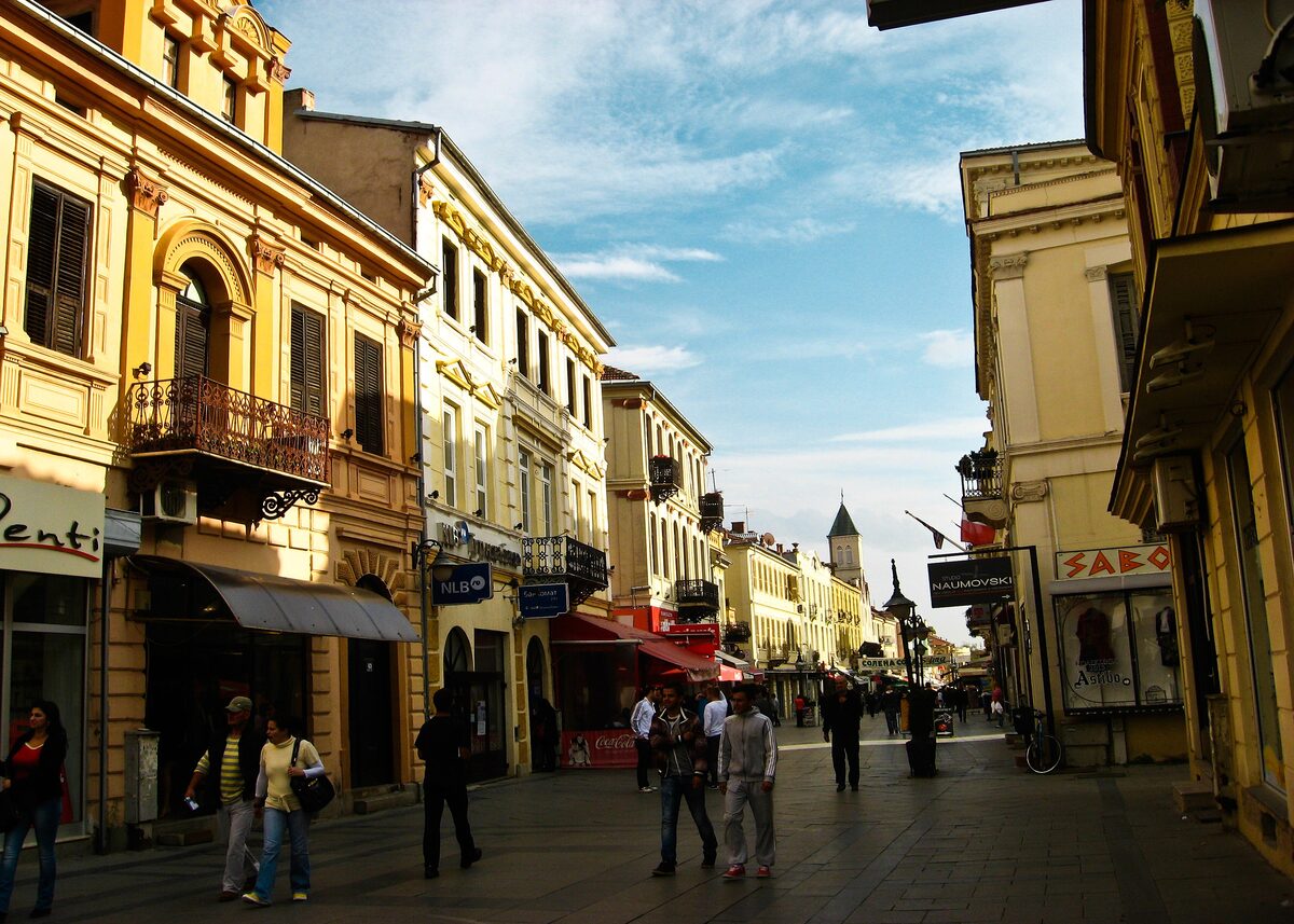 The pedestrian Širok Sokak in Bitola, with cream and yellow facades and a clock tower at the far end