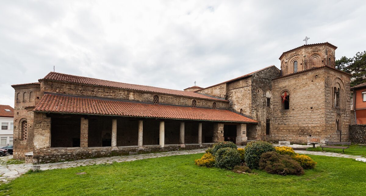 The stone arcade of St. Sophia with a grass lawn in front of the church
