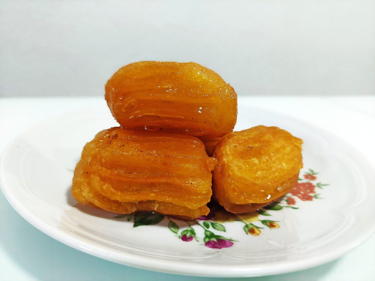 Golden fried tulumba soaked in syrup on a floral plate