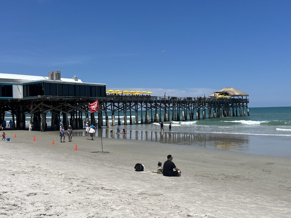 The Cocoa Beach Pier stretching into the Atlantic from a wide sandy beach on a sunny day