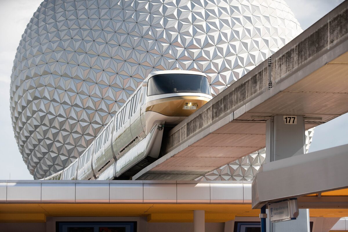 A monorail train gliding past the silver geodesic sphere of Spaceship Earth at EPCOT
