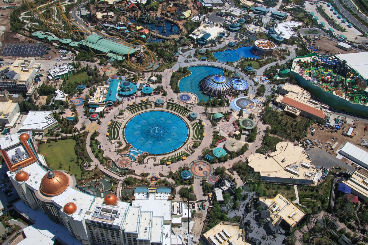 Aerial view of Celestial Park, the round hub of Epic Universe, with its blue fountain pool and the surrounding themed lands