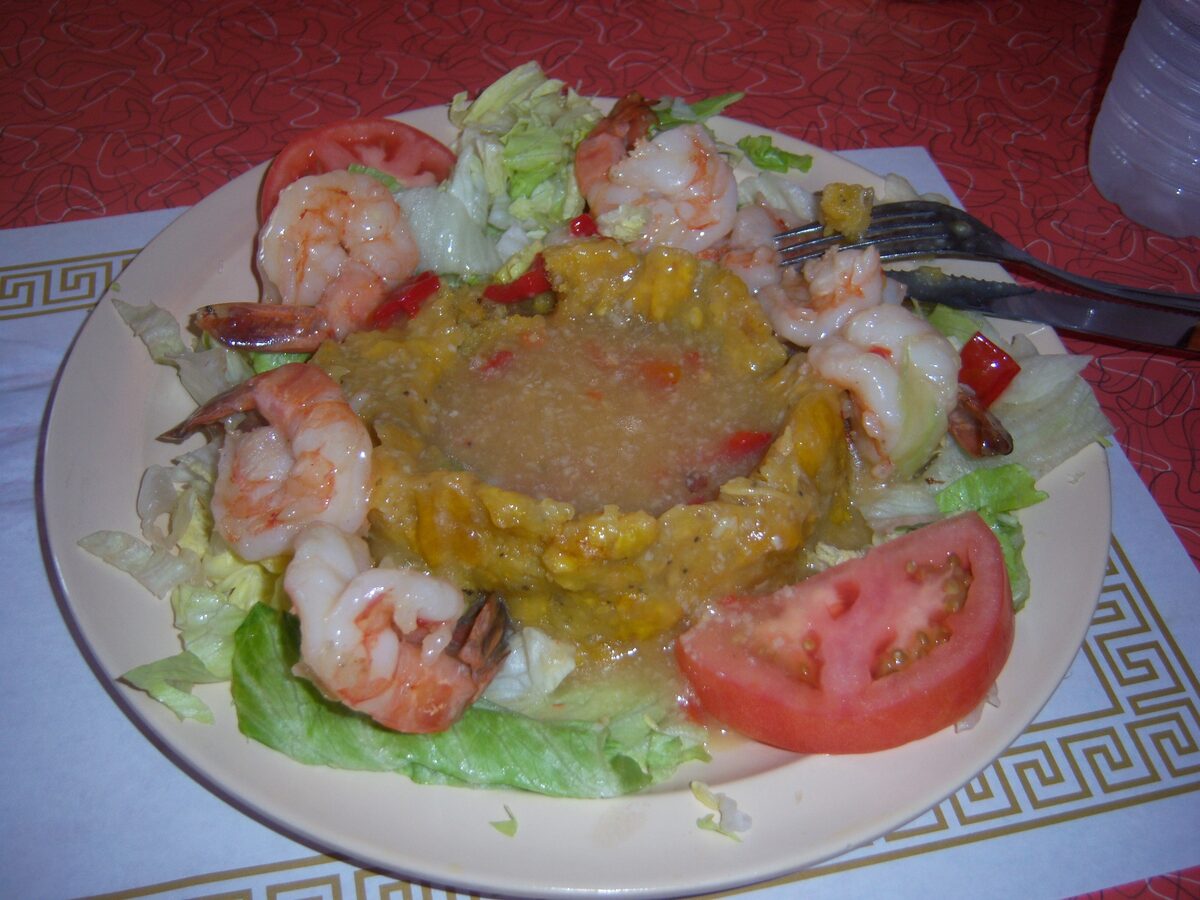 A mound of mashed plantain mofongo ringed with shrimp, lettuce and tomato on a plate