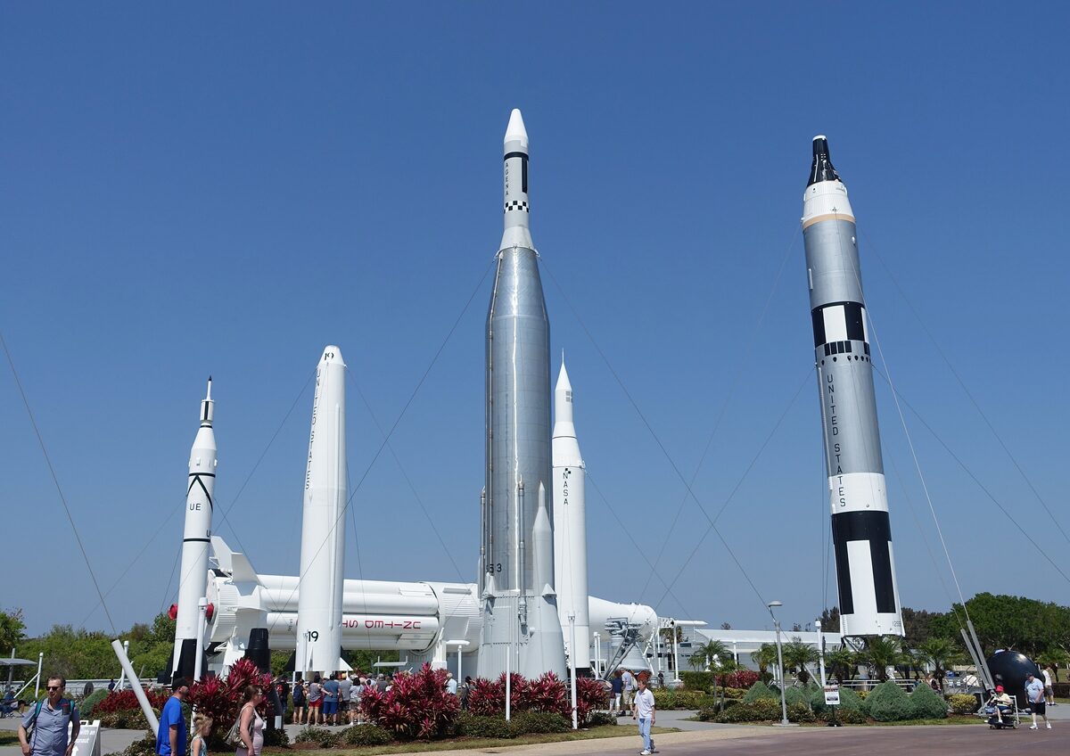 Vintage rockets standing upright against a blue sky in the Rocket Garden at Kennedy Space Center, with flower beds in front