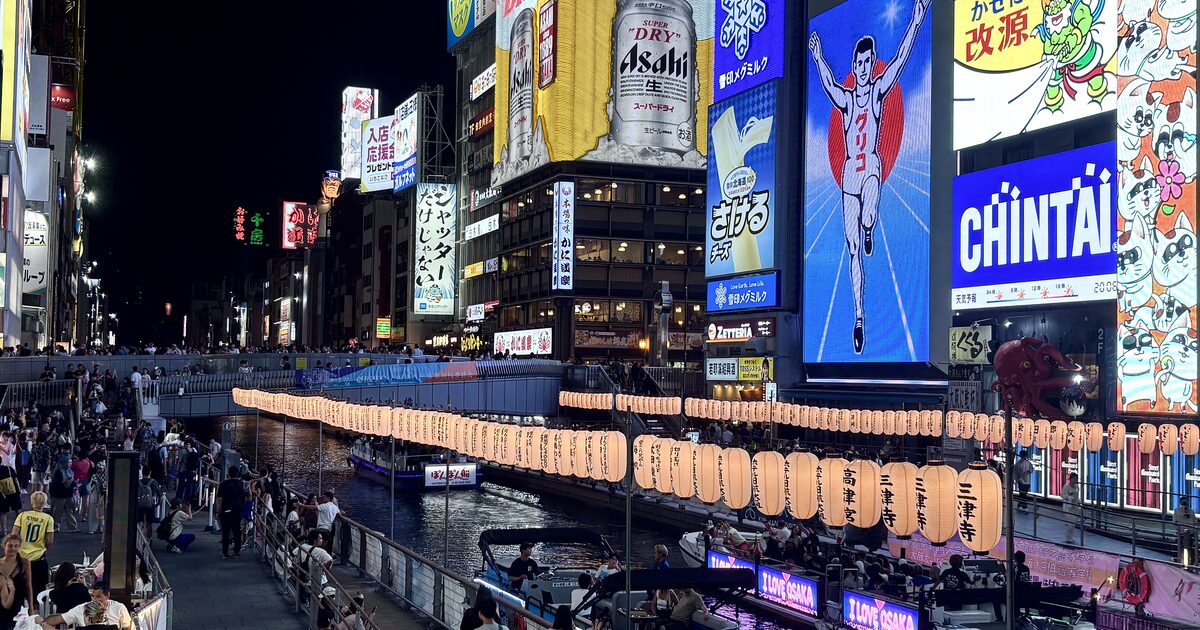 The Dotonbori canal in Osaka at night with the lit signs and the Glico runner on the riverbank