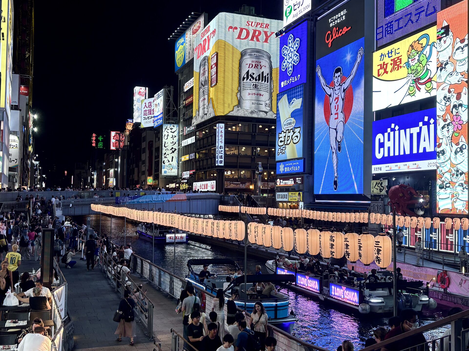 The Dotonbori canal in Osaka at night with the lit signs and the Glico runner on the riverbank