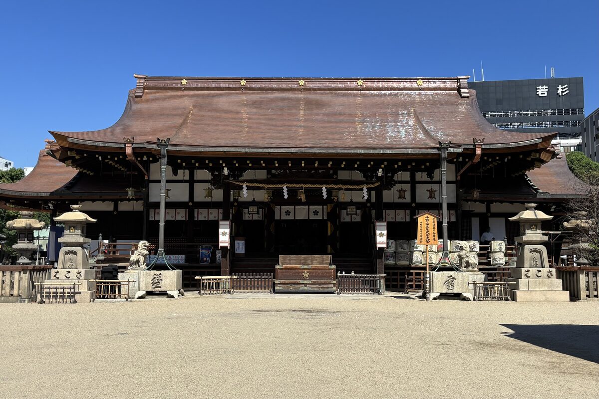 The main hall of Osaka Tenmangu shrine with stone lanterns in the sandy courtyard