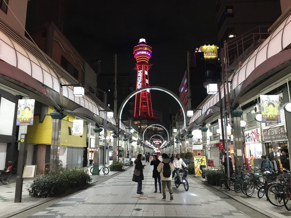 Tsutenkaku tower lit red at night at the end of the Shinsekai shopping street