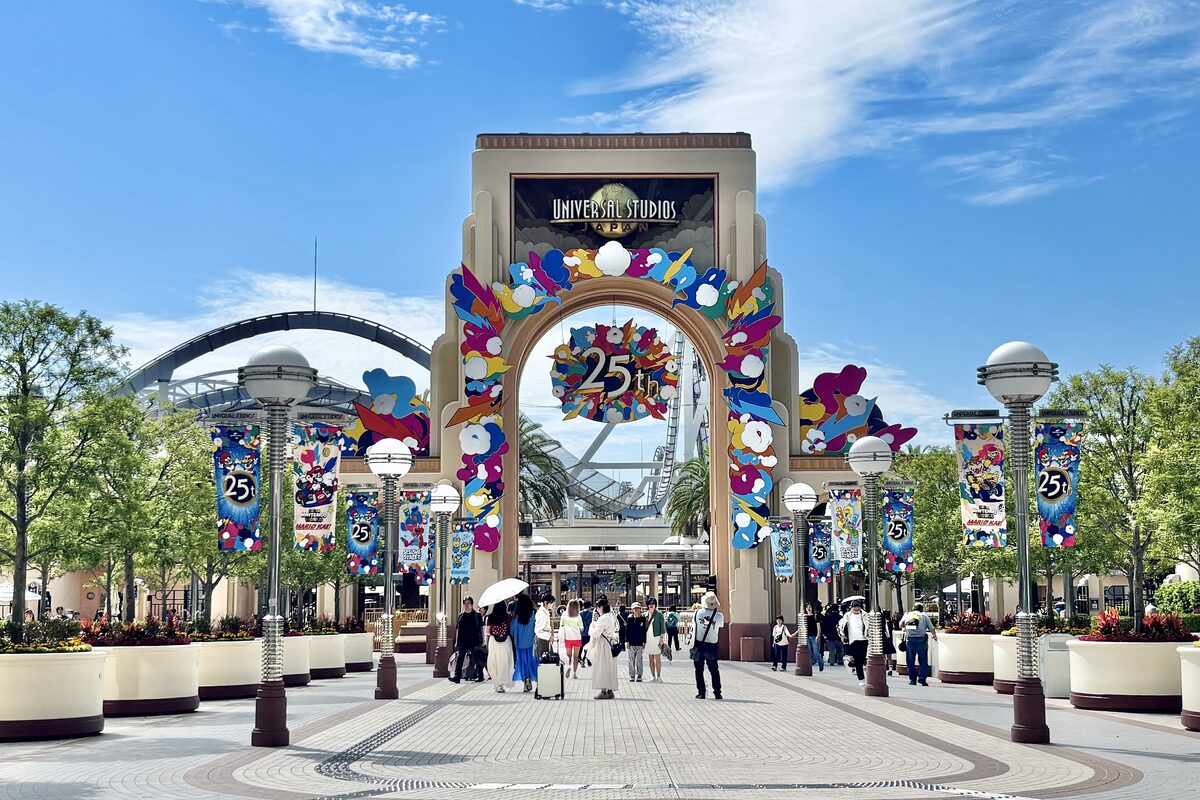The entrance arch of Universal Studios Japan with colorful banners and visitors walking in