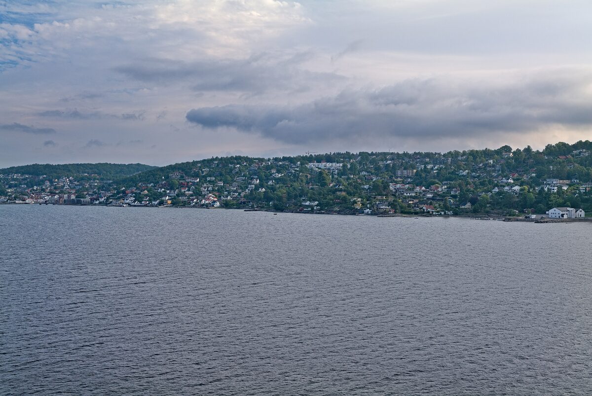 The white houses of Drøbak on the green shore of the Oslofjord seen from the water