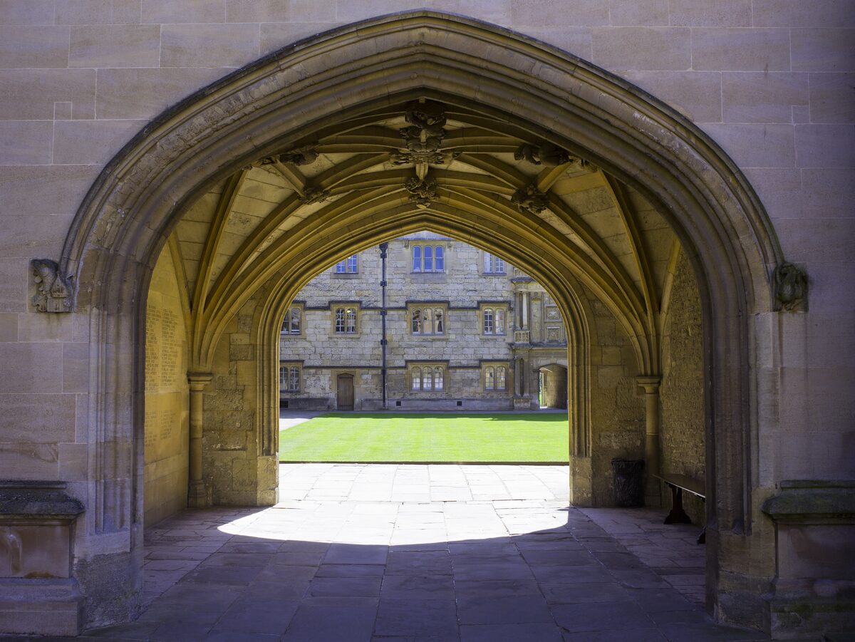 A vaulted stone gateway at Merton College, Oxford, opening onto a sunlit quadrangle