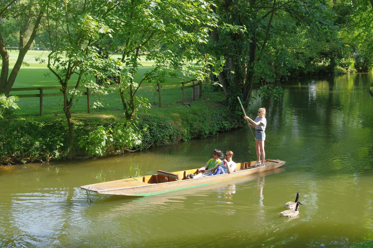 Punts on the River Cherwell in Oxford, with a person standing at the back pushing with a long pole