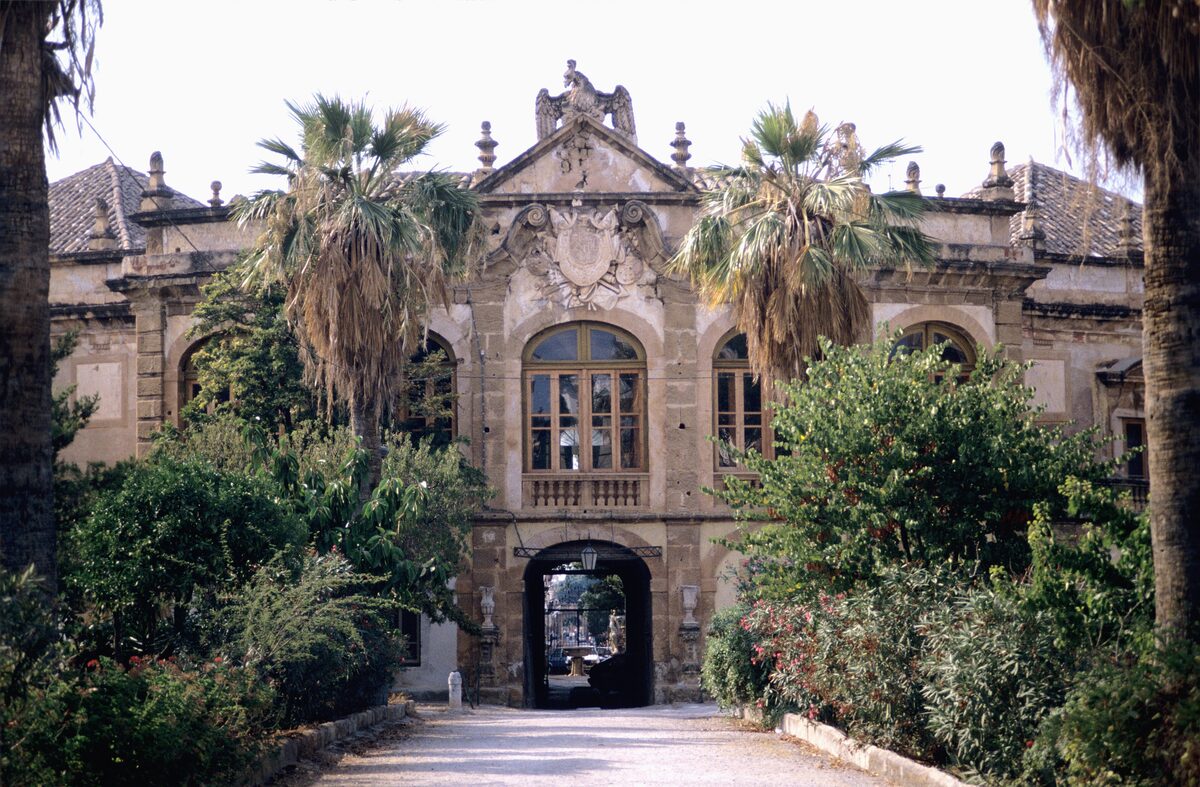 The gate and facade of Villa Palagonia among palms