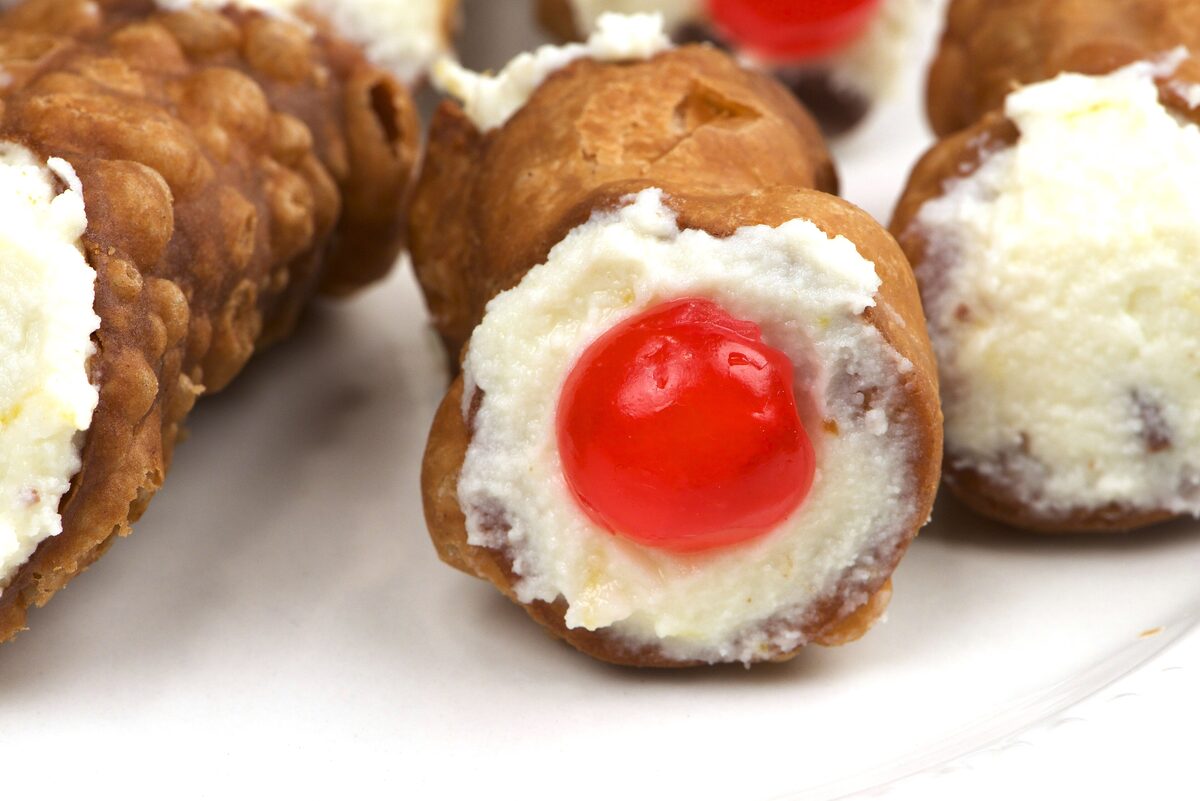 Cannoli filled with ricotta and topped with a candied cherry