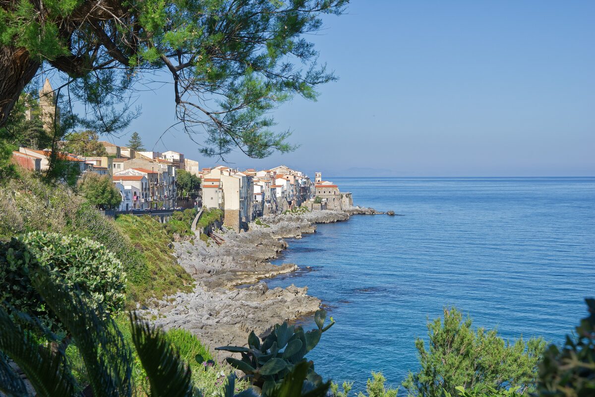 Cefalù's old houses on the rocky shore, seen from a path above the sea