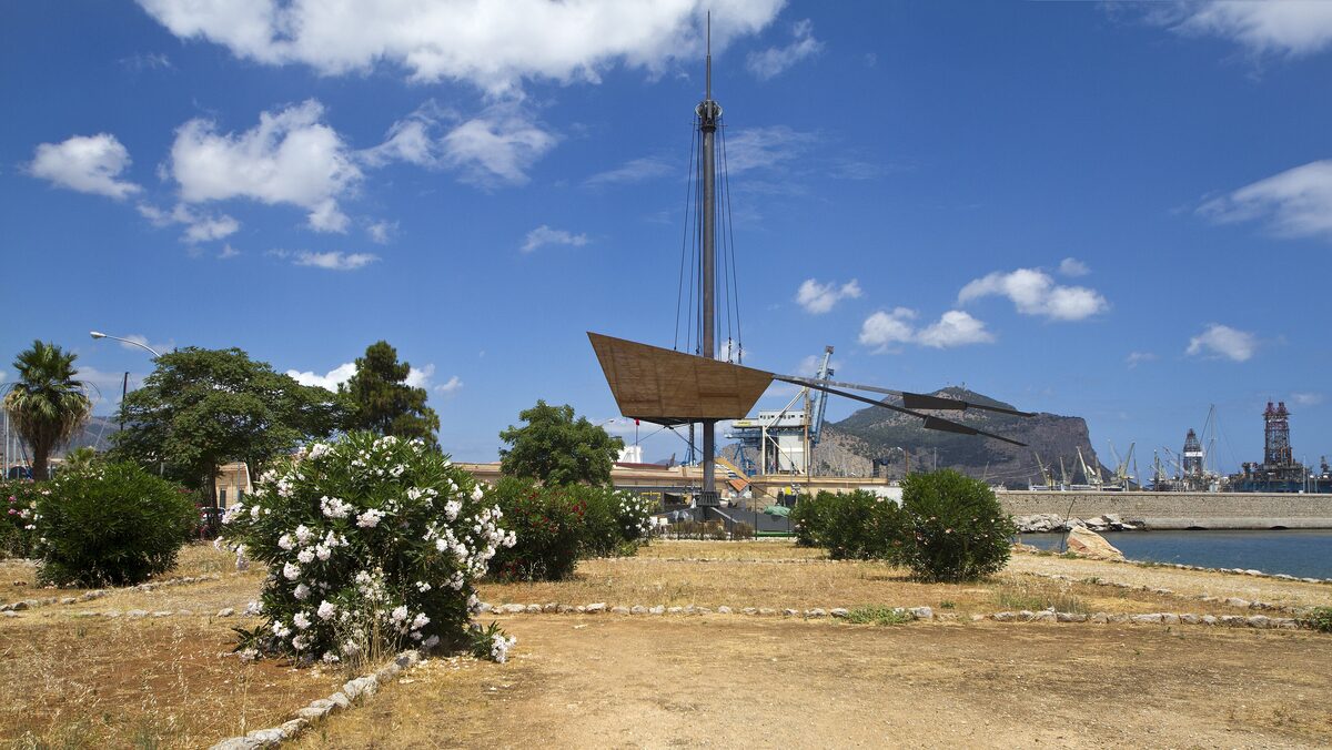 The Foro Italico lawn by the sea, with a ship sculpture and the harbor behind