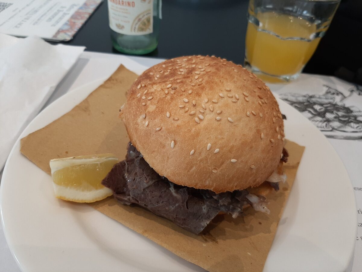 A sesame bun filled with sliced spleen, served with a lemon wedge
