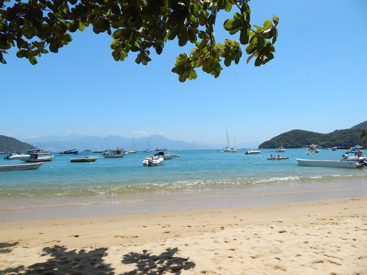 Fishing and tour boats anchored in the clear bay in front of the sandy beach at Vila do Abraão
