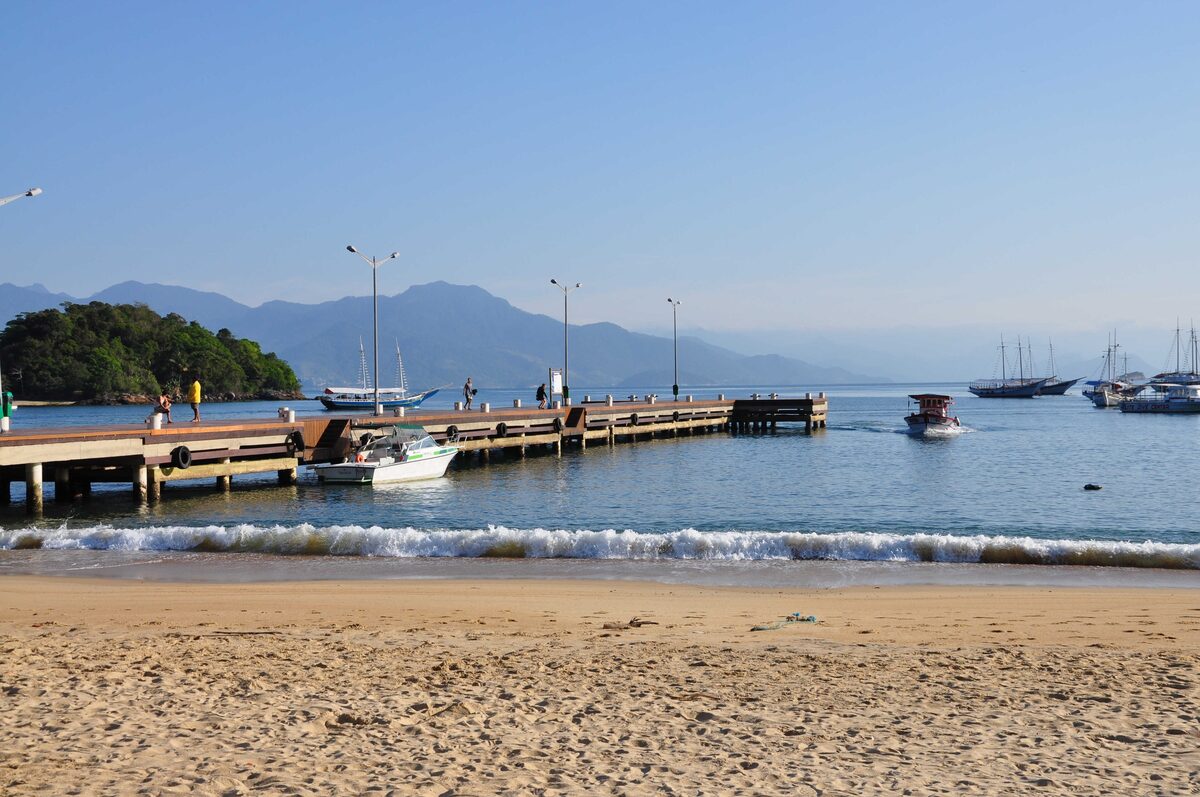 The wooden pier at Vila do Abraão, with boats moored in the bay and the beach alongside