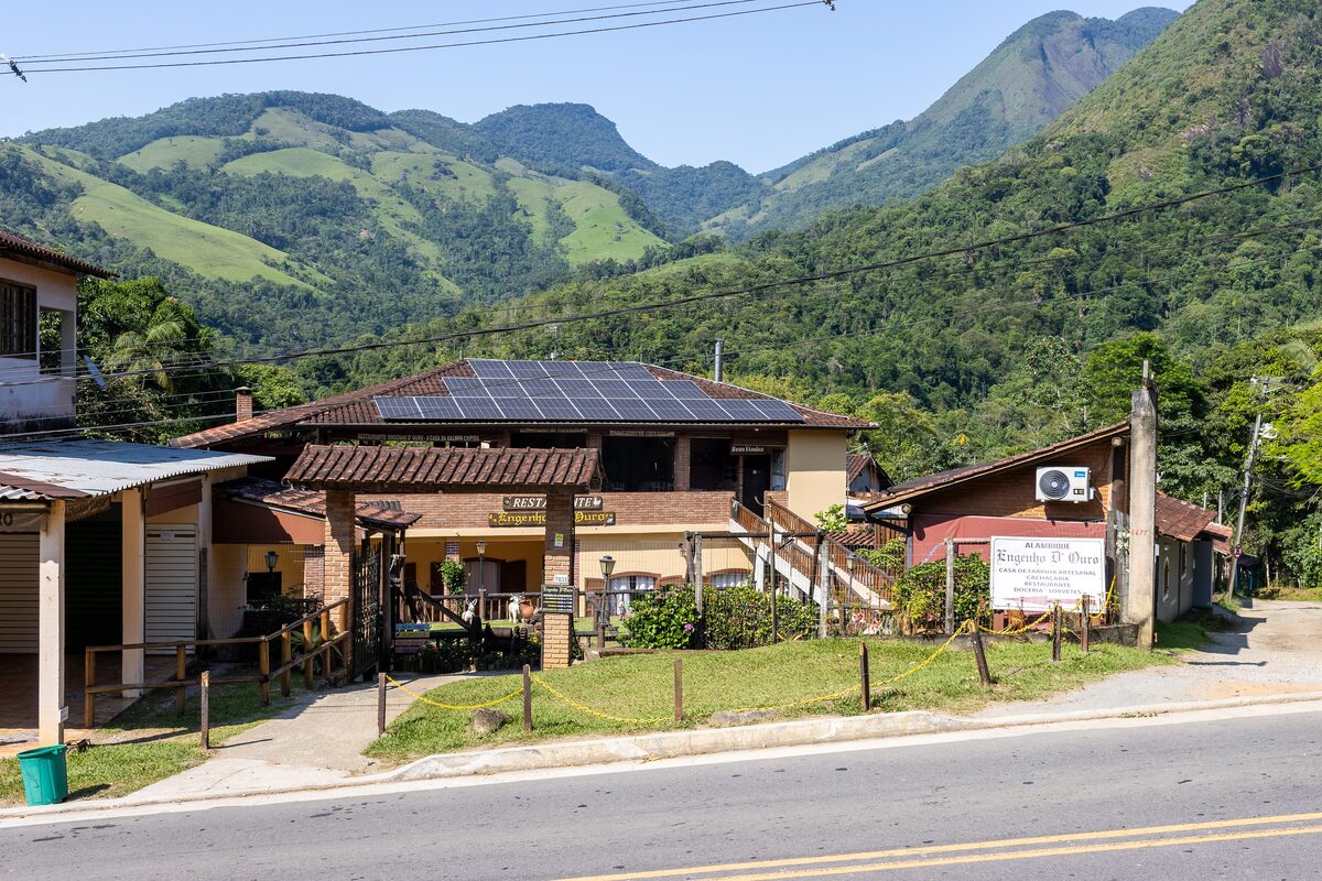The Engenho D'Ouro restaurant building beside the road, with green hills behind