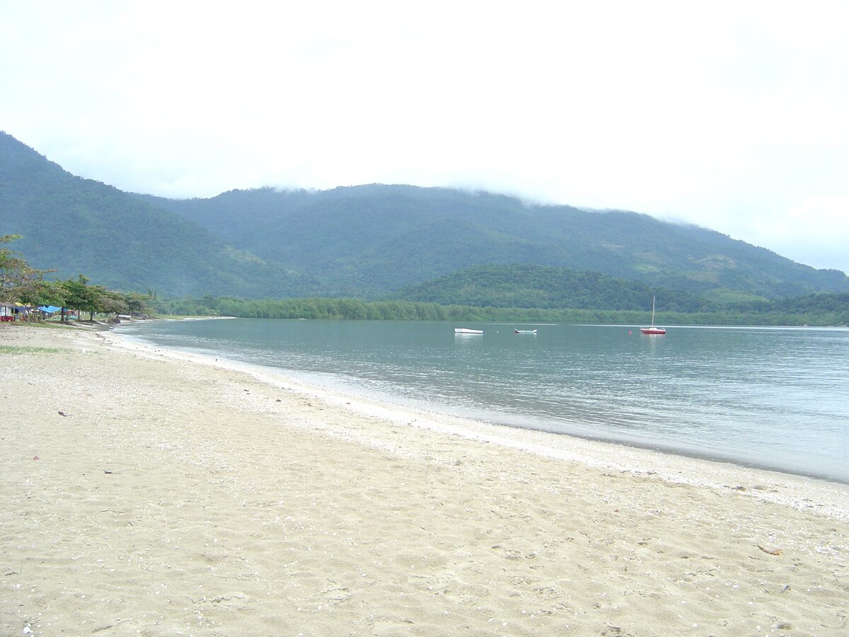 Wide sand and calm water at Praia do Jabaquara in Paraty, with boats and mountains across the bay