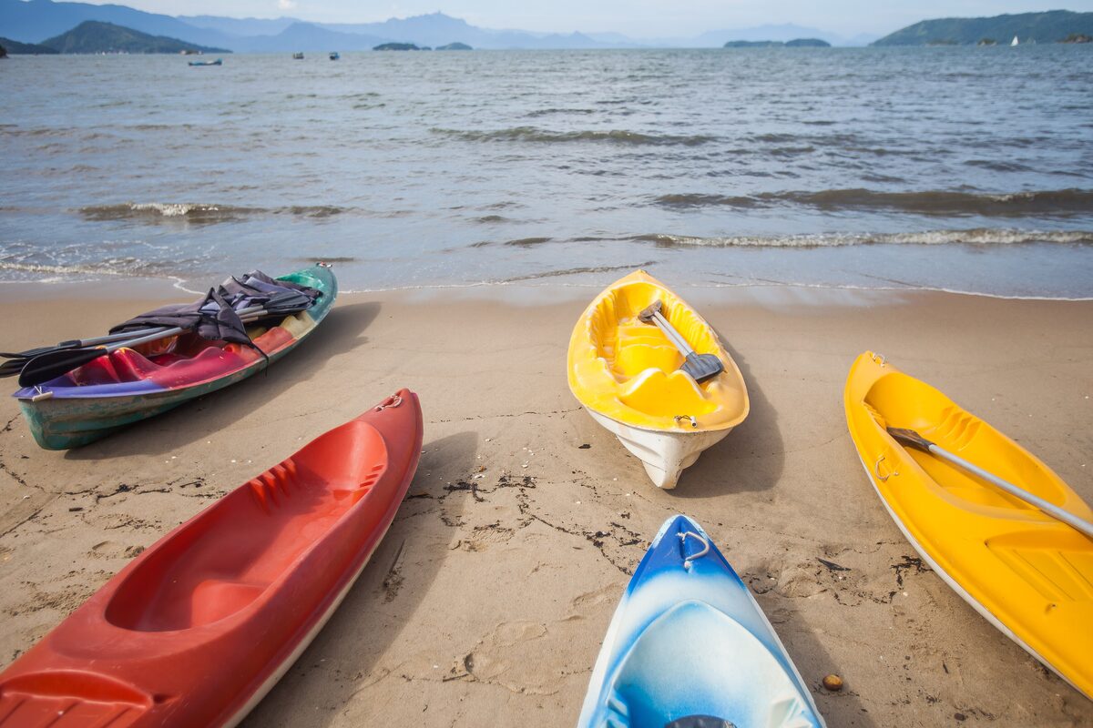 Colorful sea kayaks pulled up on the sand at Praia do Pontal in Paraty, with the bay and islands behind