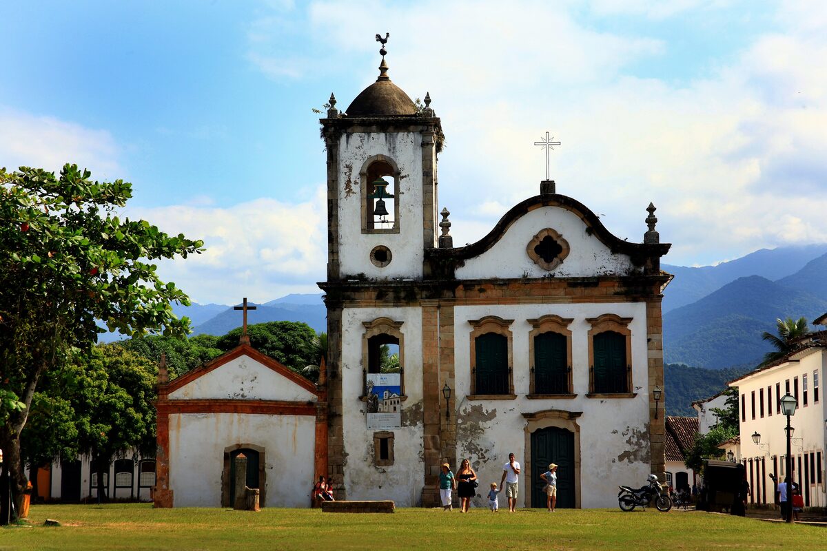 The white facade and bell tower of the Igreja de Santa Rita on a grassy square in Paraty