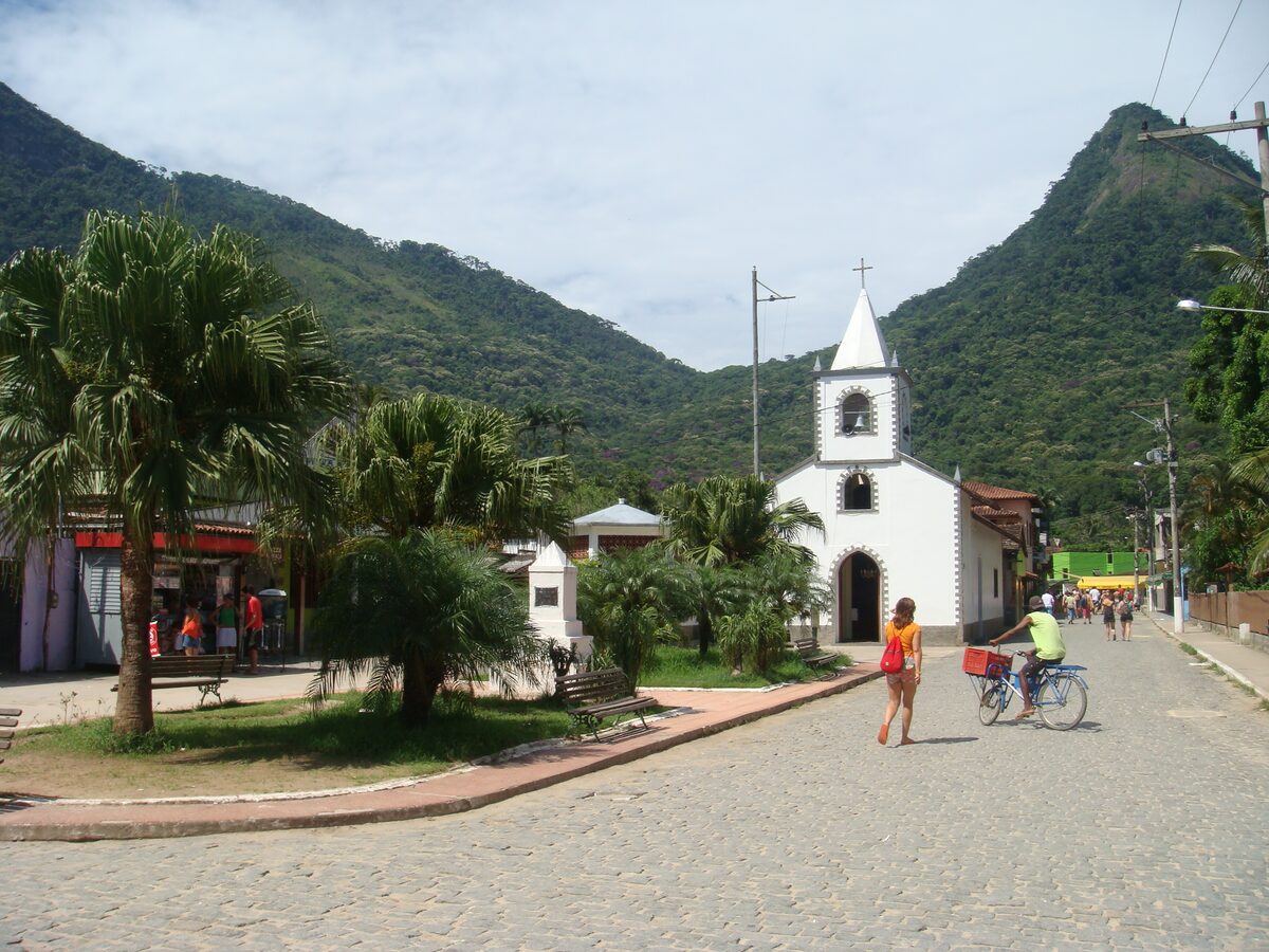 The white São Sebastião church on the street of Vila do Abraão, with palms and hills behind