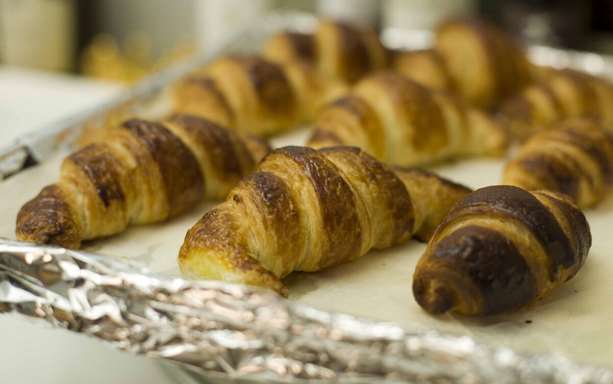 Crescent-shaped croissants fresh from the oven on a baking tray