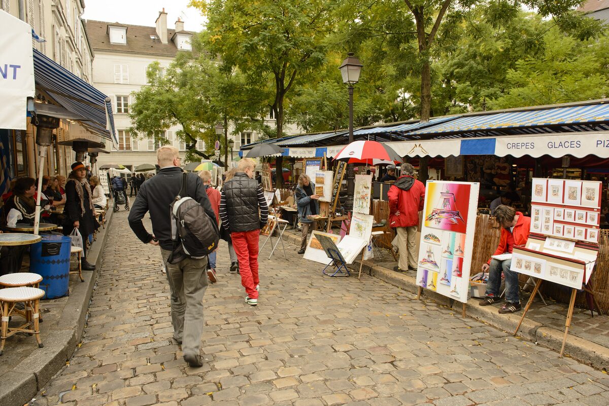 Painters' stalls and café terraces under the trees on the cobbled Place du Tertre in Montmartre