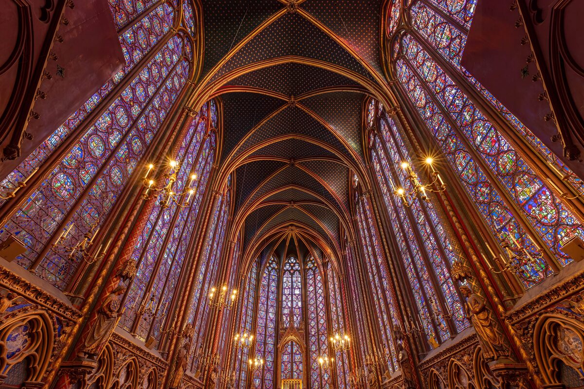 The upper chapel of Sainte-Chapelle, its vaulted ceiling and stained-glass windows glowing red and blue