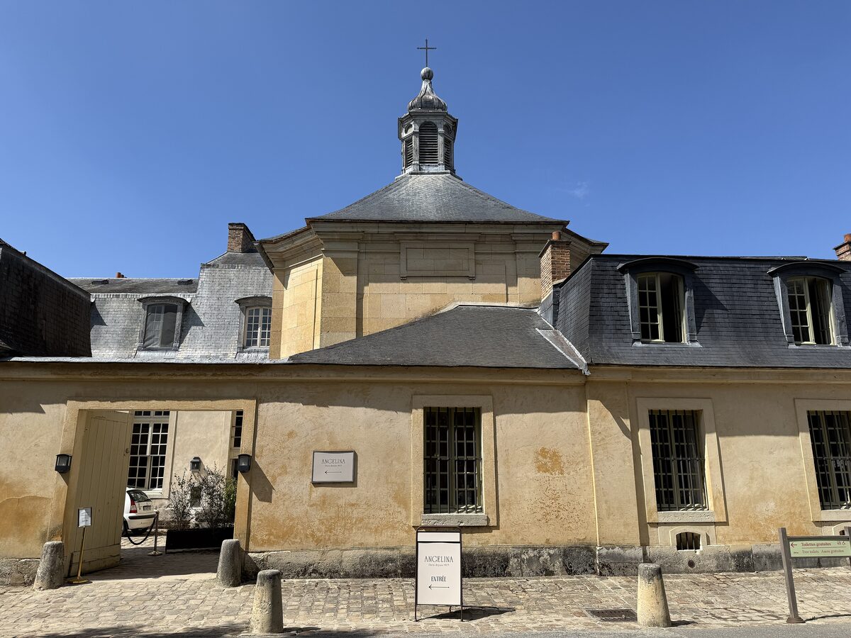 The chapel of the Petit Trianon, a pale stone building with a small dome under a blue sky