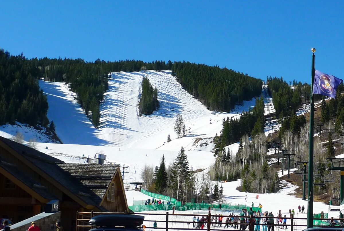Groomed snow runs at Deer Valley Resort with a crowd at the base and flags above the lift
