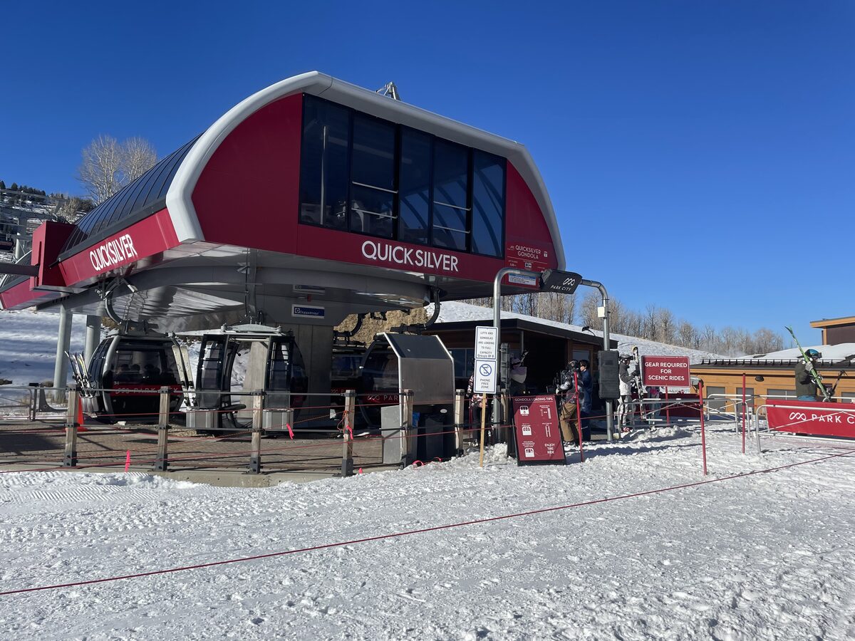 The red Quicksilver Gondola station at Park City Mountain, with cabins under the roof and packed snow in front