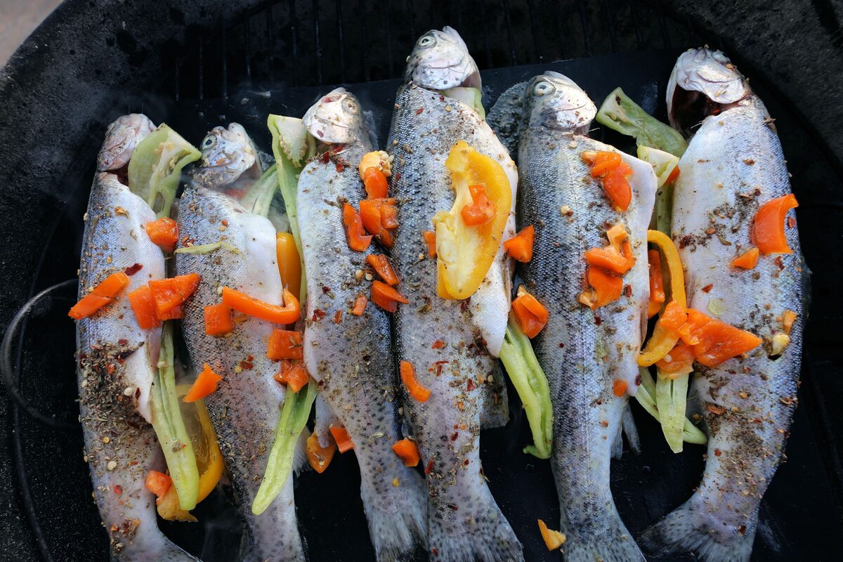 Whole trout stuffed with peppers and spices, cooking on a barbecue grill