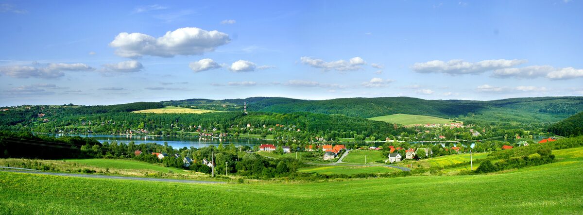 Green hills around the lake and village of Orfű under a blue sky with small clouds