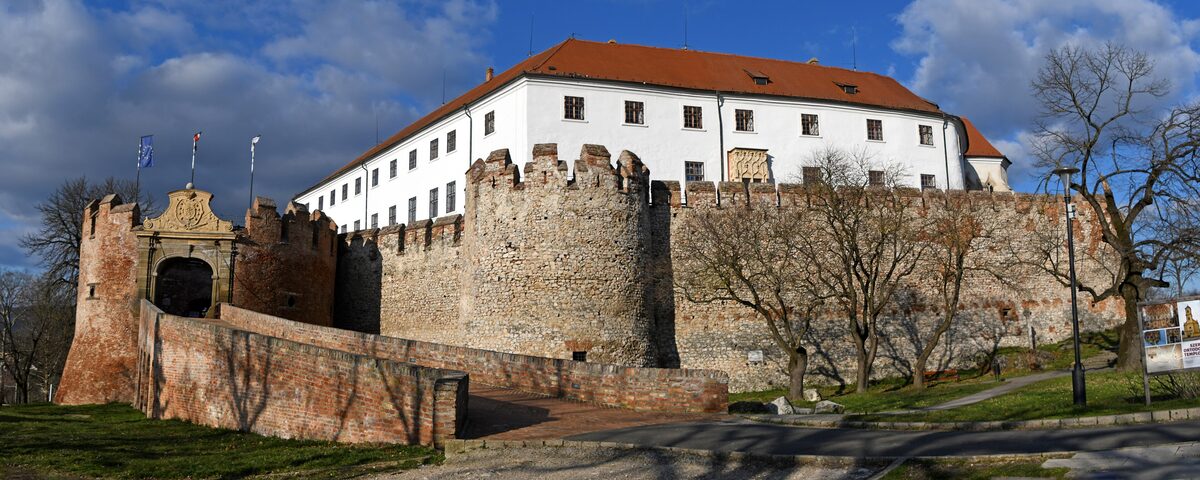 Siklós Castle, with medieval walls, round towers and a gate in front of the white main building with a red roof