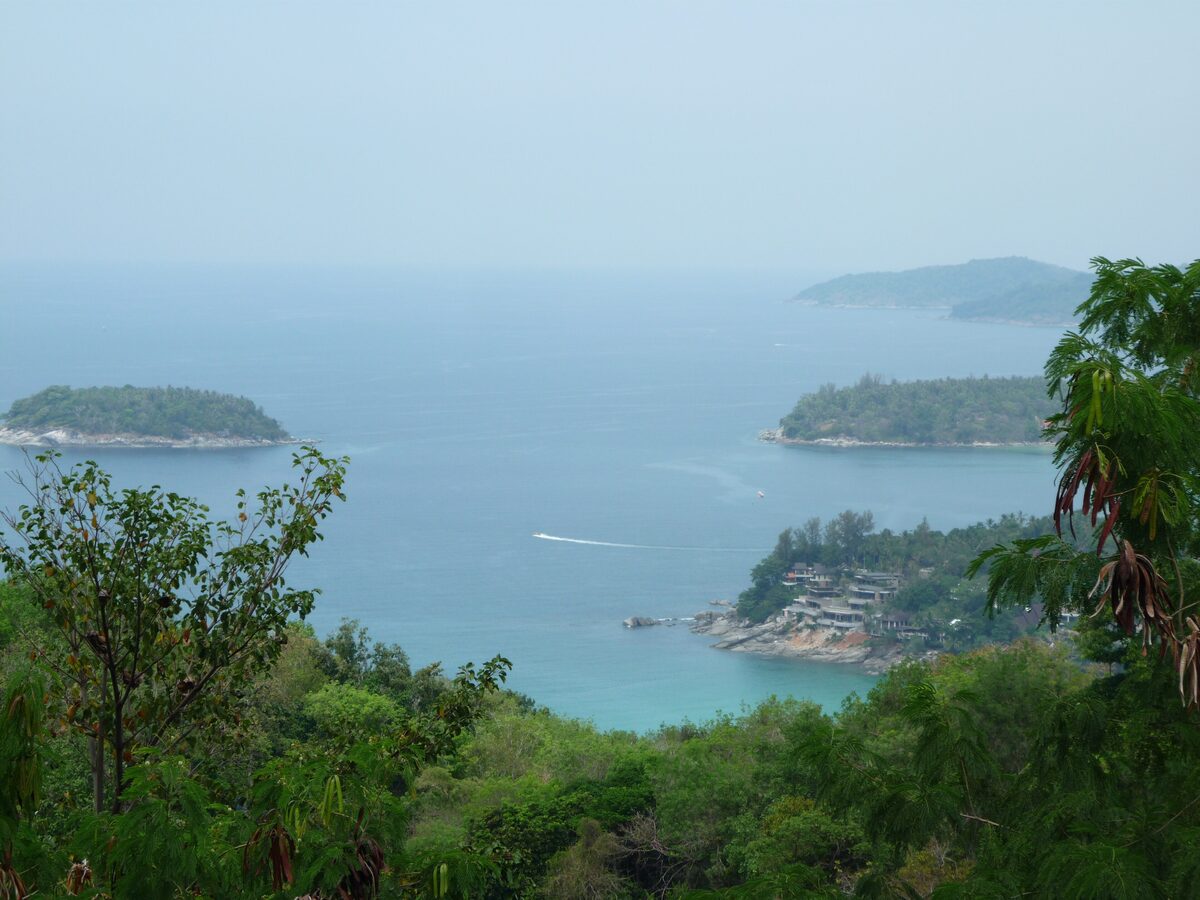 Hazy view of turquoise sea through the trees from Karon Viewpoint, with Ko Pu and two forested headlands below