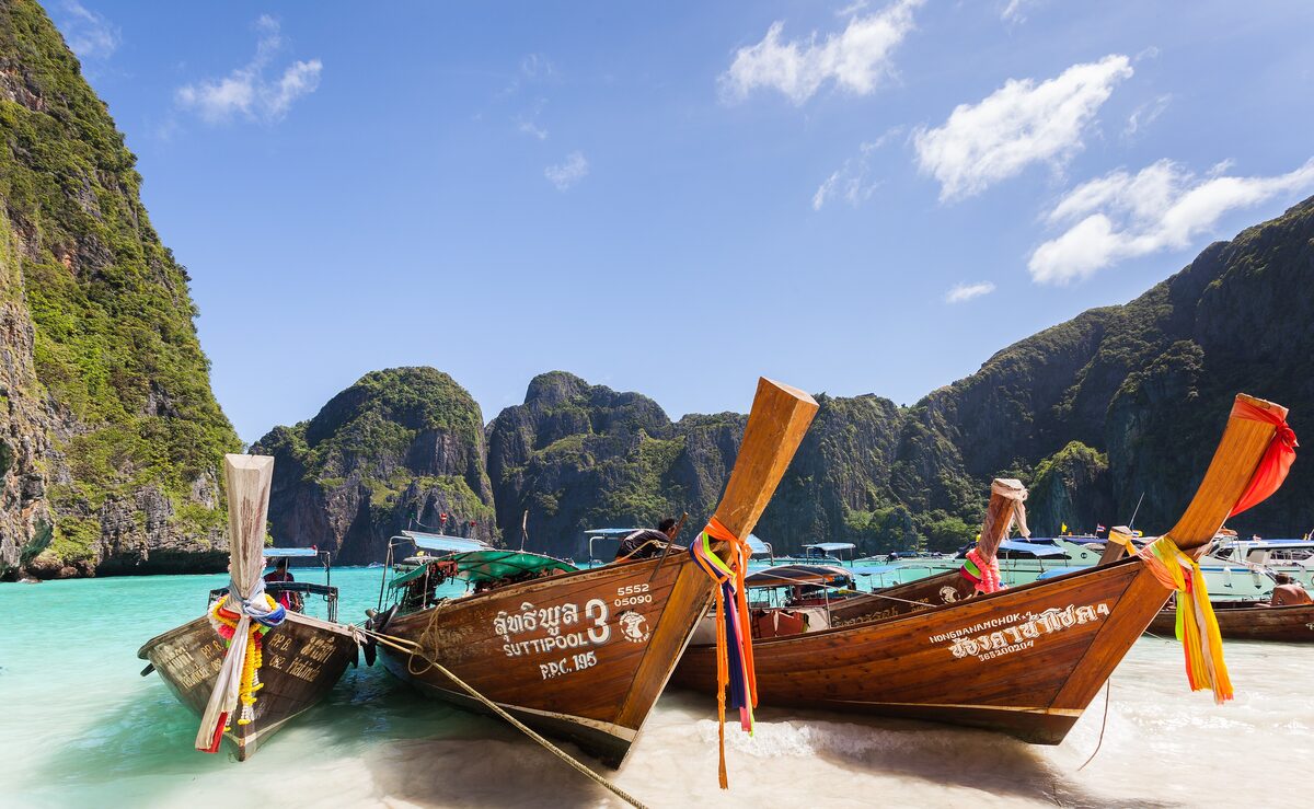Longtail boats on the shore at Maya Bay, with limestone cliffs rising behind the beach