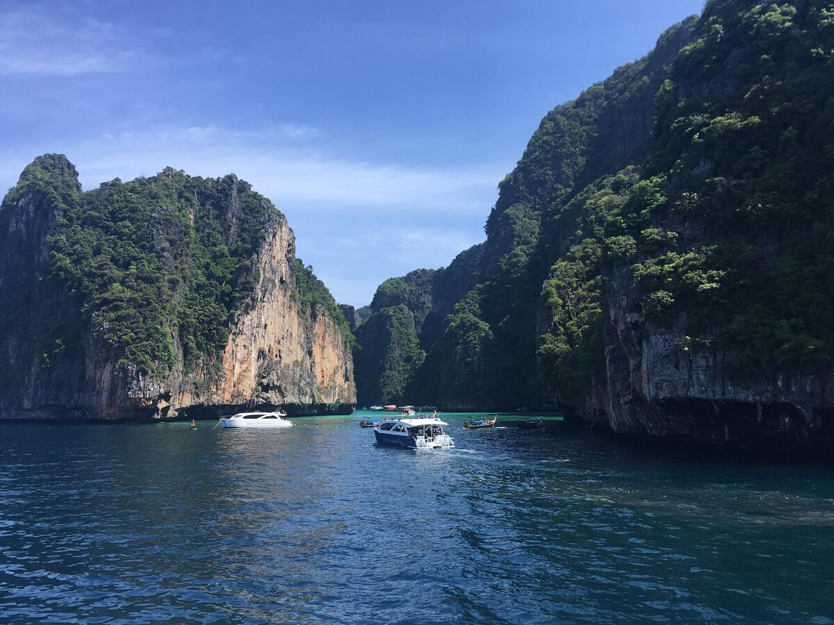 A boat in the green water of Pileh Lagoon between tall limestone cliffs on Phi Phi Leh