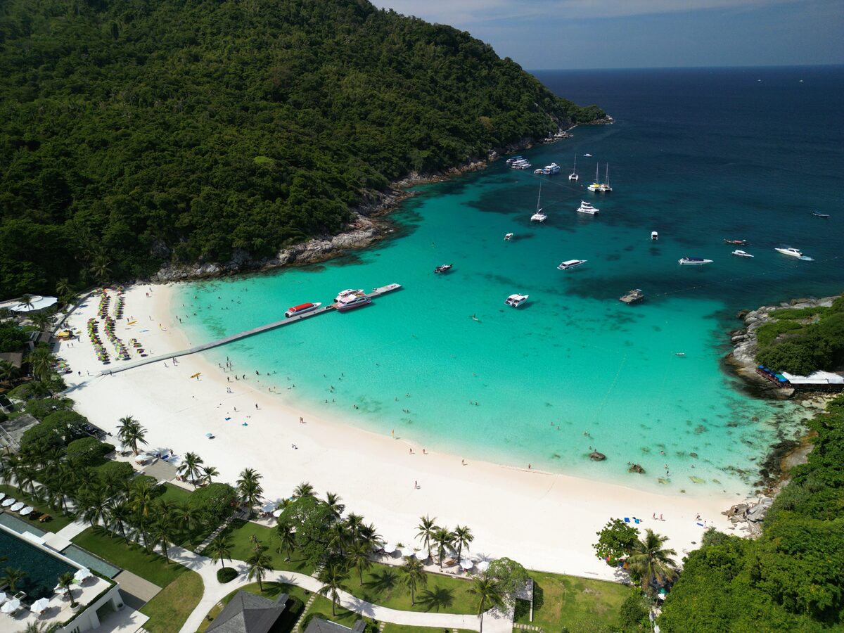 Aerial view of a white-sand bay on Ko Racha Yai, with turquoise water and moored boats