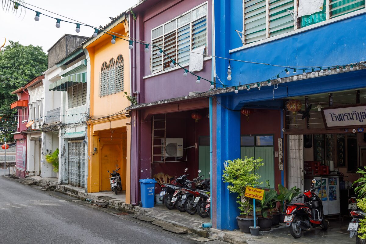 Colorful shophouses with shutters, lanterns and parked motorbikes on Thalang Road in Phuket Old Town