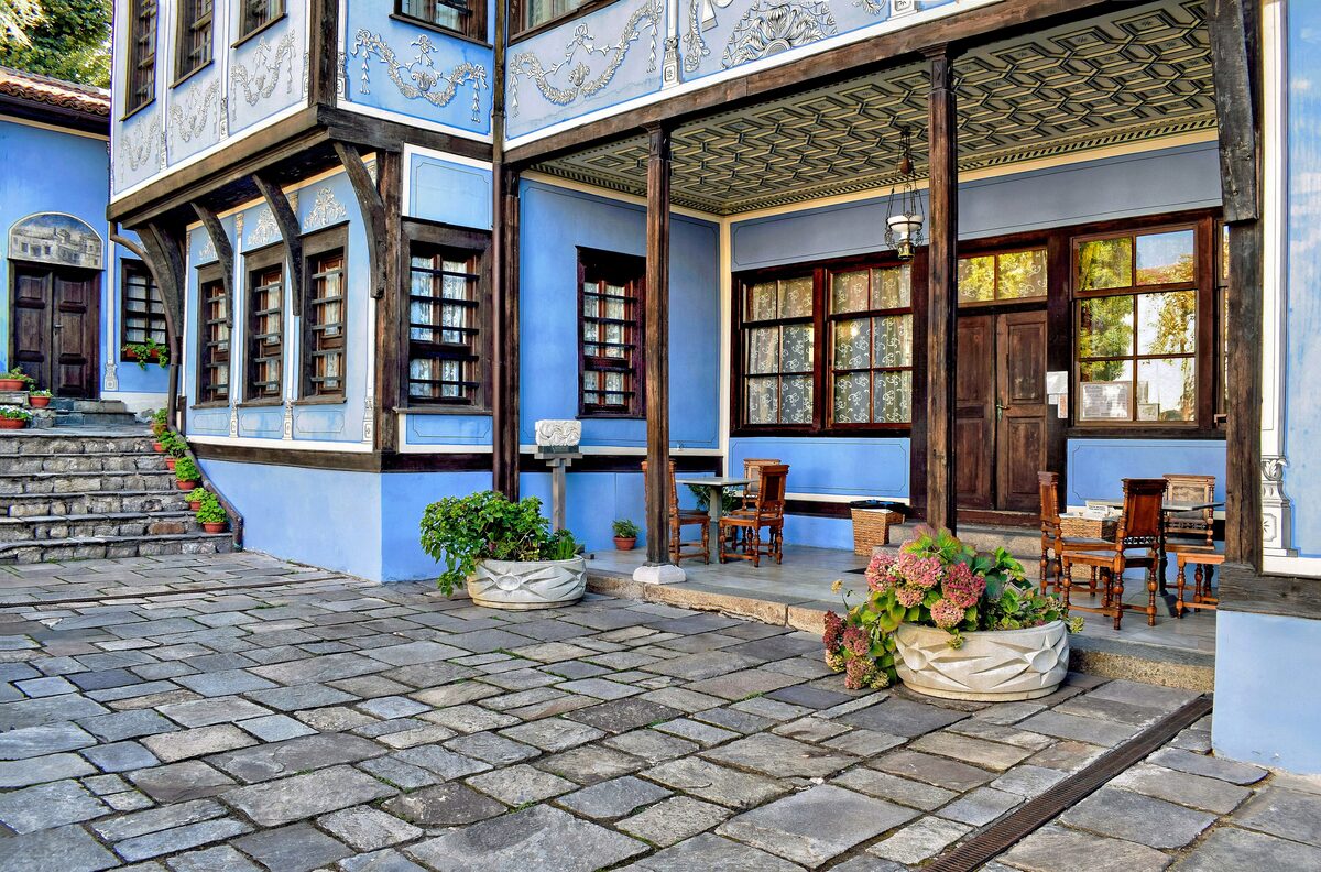The courtyard of Hindliyan House, a sky-blue Revival-era merchant house with a carved wooden porch ceiling, stone paving and flowering pots.