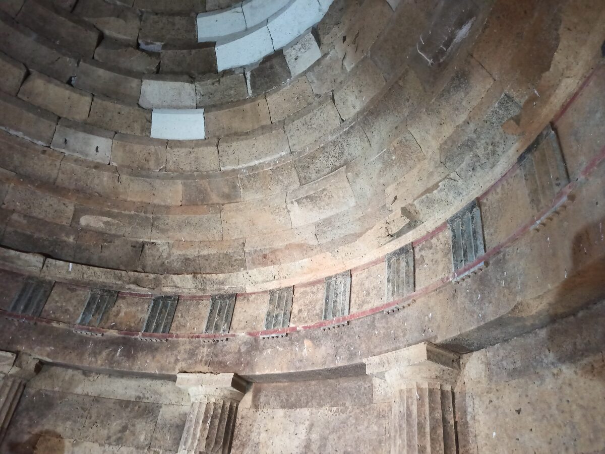 The domed round hall inside the Chetinyova mound at Starosel, with stone courses curving overhead, a frieze of carved triglyphs and fluted half-columns.