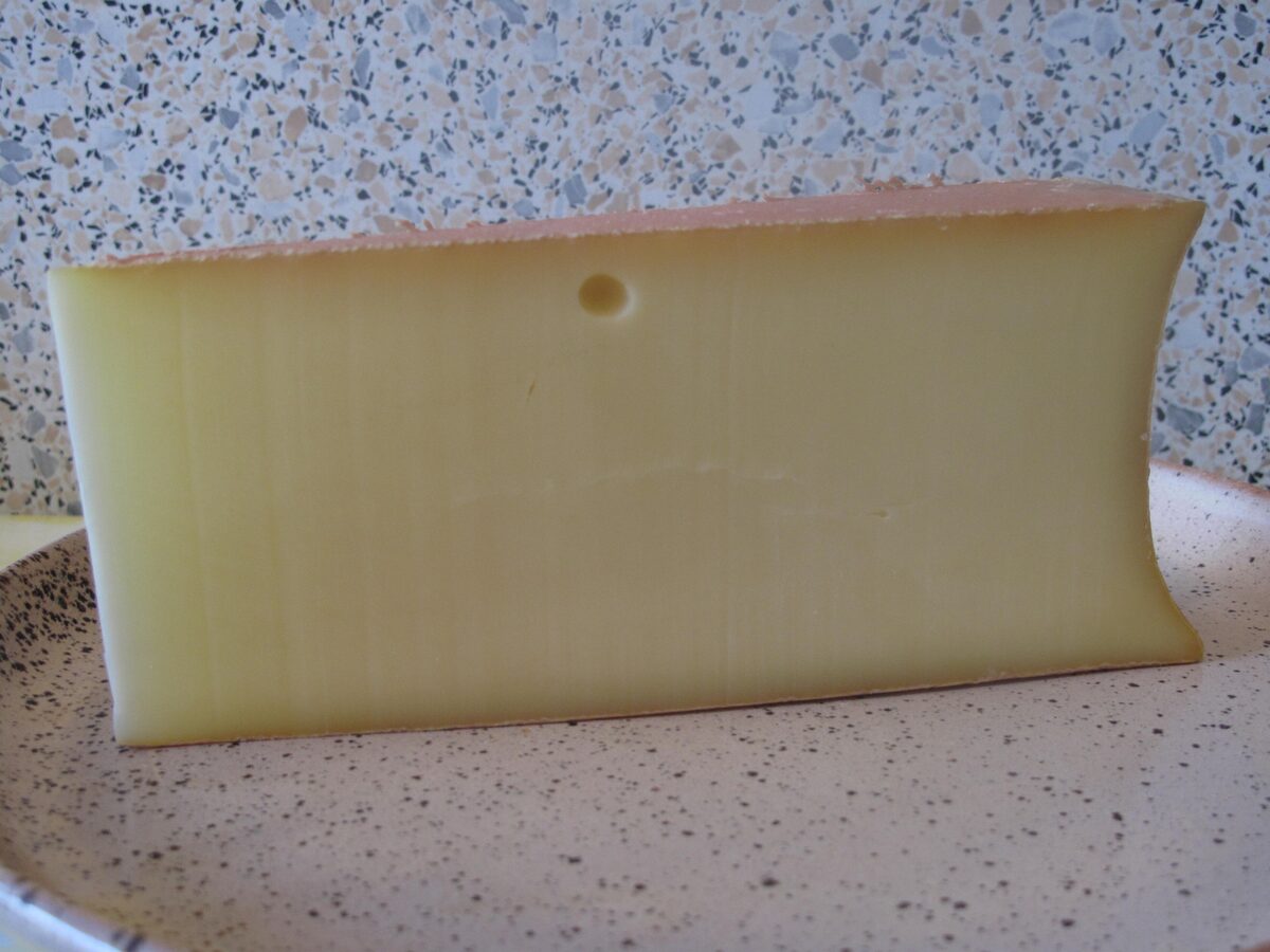 A thick wedge of Abondance cheese with its pale yellow paste and a few small holes