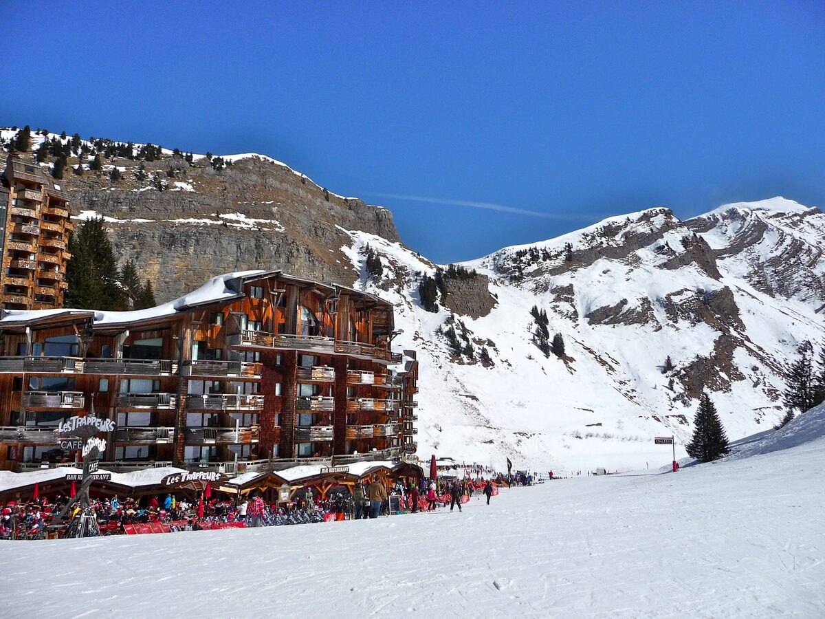 Apartment buildings at the edge of the Avoriaz pistes, with skiers and a terrace in snow