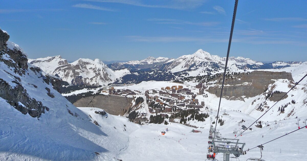 Avoriaz village seen from a chairlift above snowy pistes, with snowy peaks behind