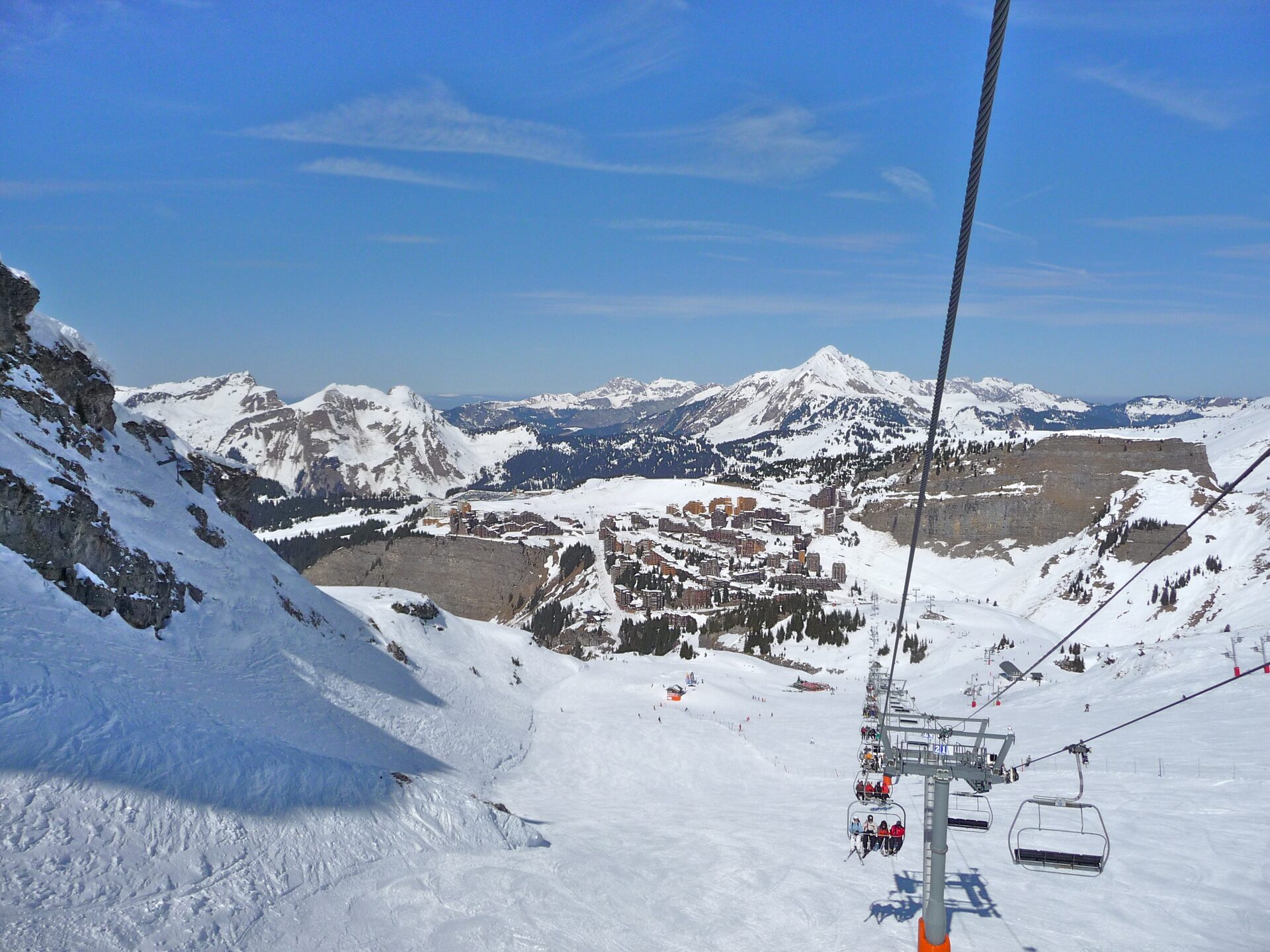Avoriaz village seen from a chairlift above snowy pistes, with snowy peaks behind